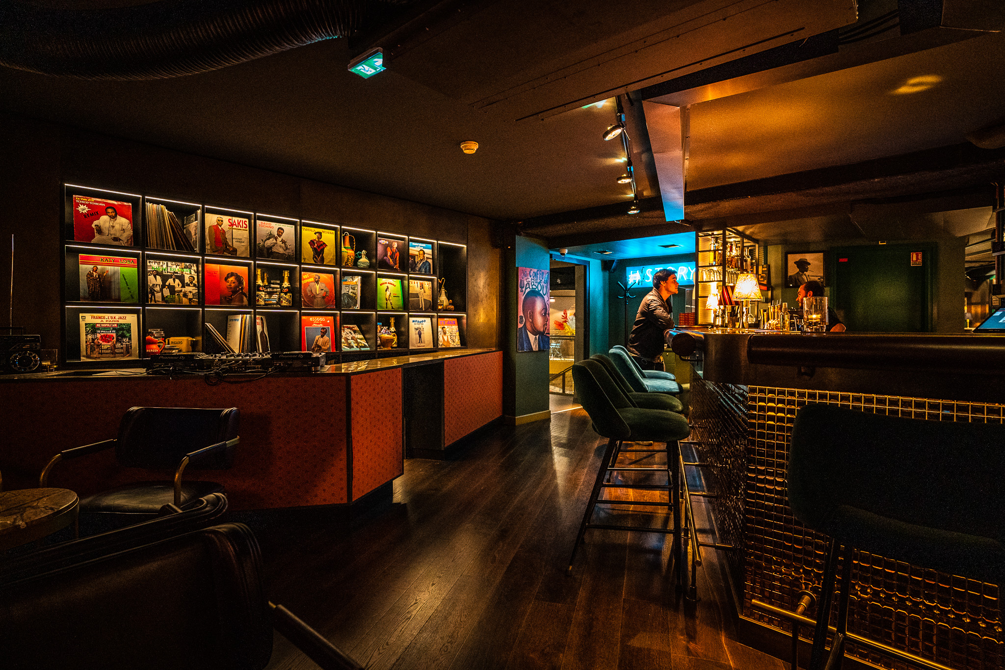 The interior of the Sape Bar, with a DJ booth and several records on the wall as well as a bounter with bar stools